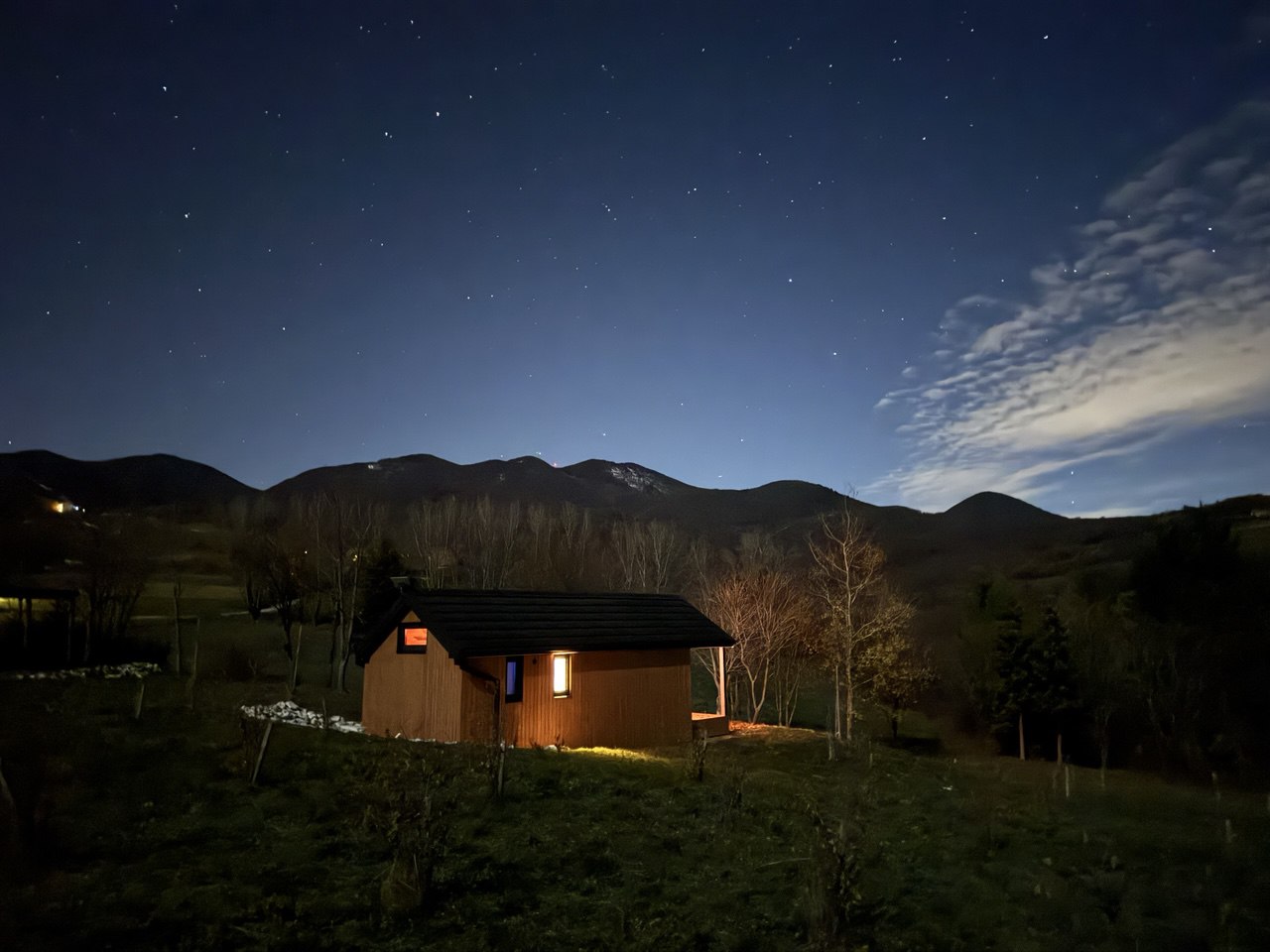 Kućica osvijetljena noću pod zvjezdanim nebom
